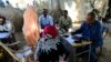 FILE - Yasir Ahmed Mohamed, seated at right, special prosecutor for crimes in Darfur, and his team talk to women during an investigation into allegations of mass rape in Thabit, Nov. 20, 2014.