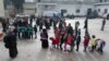 FILE - Children of Syrian families displaced from the Maaret Al-Numan region gather in the yard of a former jail turned into a makeshift refugee shelter in the northwestern city of Idlib, Dec. 31, 2019.