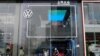 FILE - People walk past an ID. Store X showroom of SAIC Volkswagen in Chengdu, Sichuan province, China, Jan. 10, 2021.