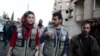 Members of OCHA (Office for the Coordination of Humanitarian Affairs), part of the United Nations, walk in the rebel held besieged town of Kafr Batna, on the outskirts of Damascus, during a distribution of humanitarian aid, Feb. 23, 2016. 
