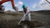A worker, wearing a protective suit and a mask, levels ground at the tsunami-crippled Fukushima Dai-ichi nuclear power plant, operated by Tokyo Electric Power Co. (TEPCO), in Okuma, Fukushima Prefecture, northeastern Japan, Wednesday, Feb. 10, 2016.