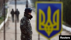 A Ukrainian soldier walks near a closed entrance gate at an airforce base in the Crimean town of Belbek March 20, 2014.
