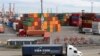 FILE - Trucks hauling shipping containers drive near containers stacked five-high at a terminal on Harbor Island in Seattle, Oct. 2, 2019.