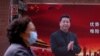  2020年3月12日，新冠病毒爆发期间，一名戴口罩的妇女从上海街头的一副中国国家主席习近平的宣传图像前走过。