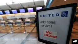 FILE - A piece of tape is affixed to a sign marking an empty line at the United Airlines ticket counter at Denver International Airport. Another scorpion has been seen on a United flight from Houston.