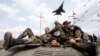 A fighter jet flies above as Ukrainian soldiers sit on an armoured personnel carrier in Kramatorsk, in eastern Ukraine, April 16, 2014. 