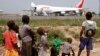FILE - A humanitarian plane of the World Food Program (WFP) unloads sacks of cereal at Mpoko international airport in Bangui, which is located near a camp for displaced people.