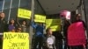 FILE - Protesters hold up signs outside a courthouse in San Francisco, April 14, 2017, where U.S. District Judge William Orrick later ruled on a lawsuit challenging President Donald Trump's executive order to withhold funding from sanctuary cities.