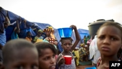 FILE - A girl balances a bowl of food on her head at an Internally Displaced People's (IDP) camp in Faladie, where hundreds have found refuge after fleeing inter-communal violence in central Mali, May 14, 2019.