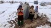 FILE - Internally displaced Afghan children stand outside their shelter in the cold at a refugee camp on the outskirts of Herat city.